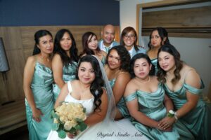 Bride surrounded by her bridesmaids in matching sage green dresses during wedding preparations.