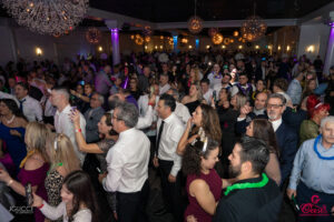 Large crowd celebrating at the Oasis Convention Centre New Year’s Eve Gala with festive lights, party hats, and dancing.