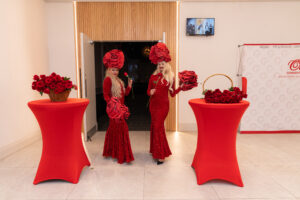 Valentine’s themed event hosts in red gowns with rose headpieces welcoming guests at Oasis Convention Centre entrance
